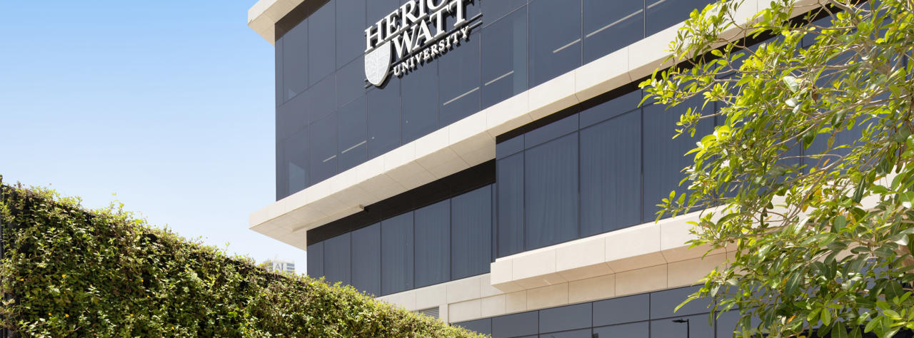 angular shot of the campus building with heriot-watt logo and green passage way at the foot of the building