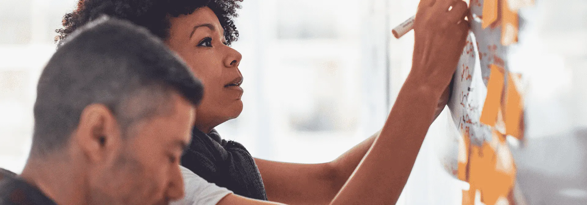 An individual writing on a post-it and placing it on a wall.