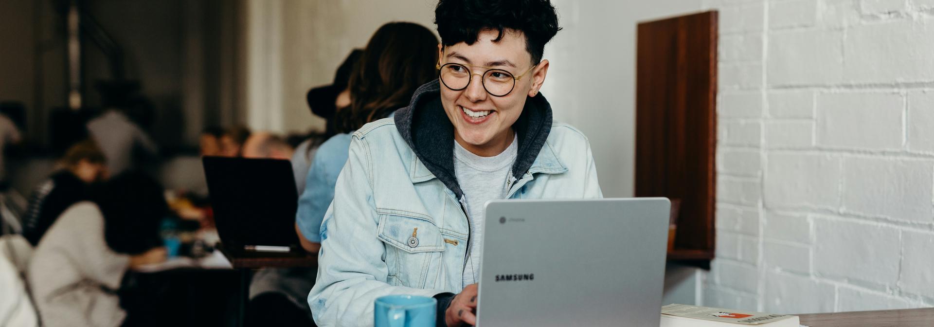 A student with a laptop sitting in a busy space