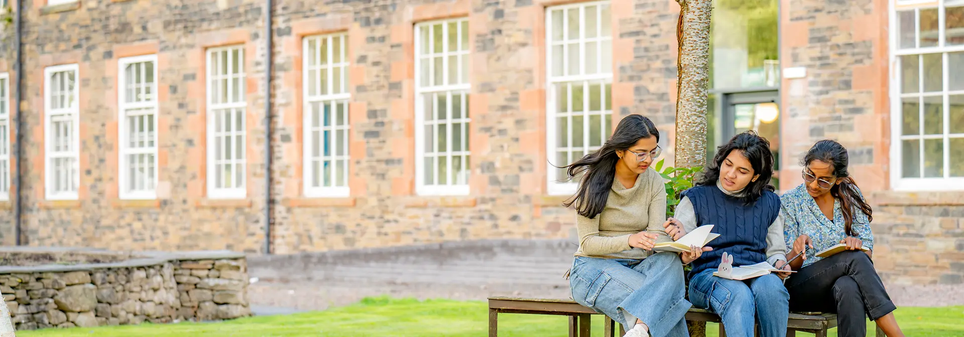 3 female students sitting outside the High Mill
