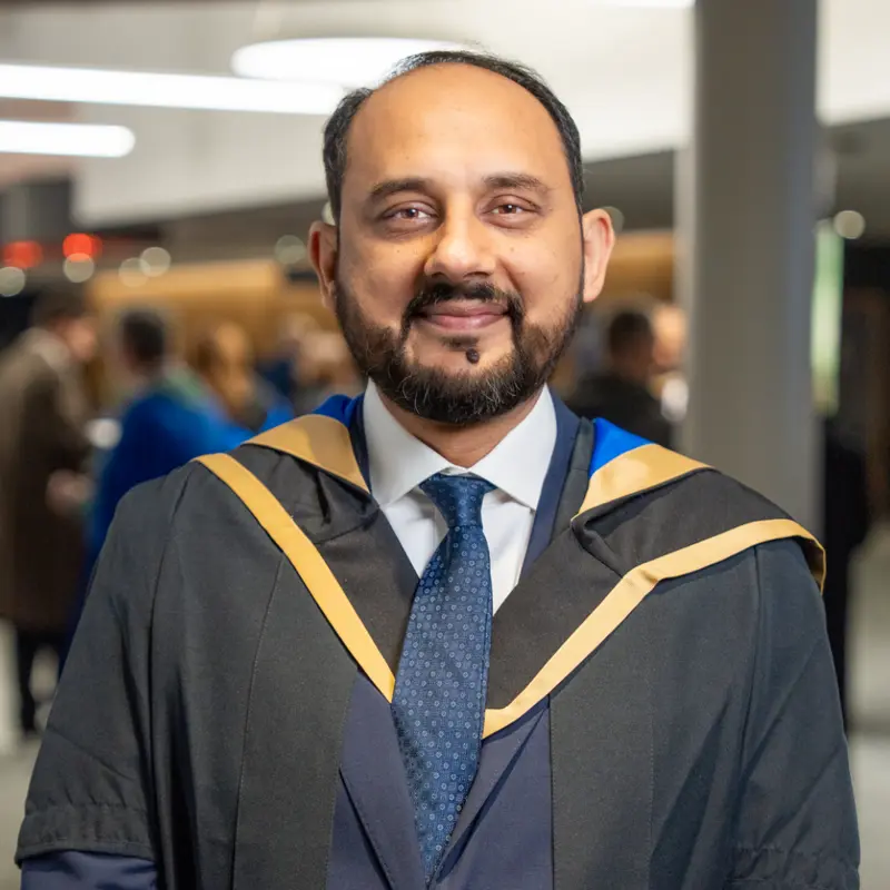 A smiling student in graduation robes.