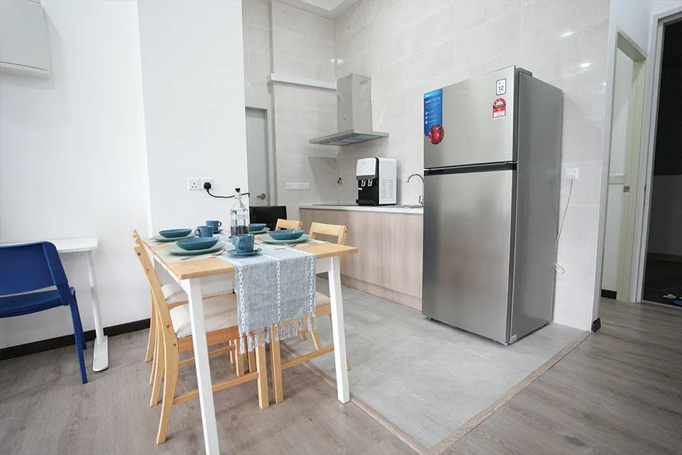 A compact kitchen featuring a refrigerator, a dining table, and chairs, designed for efficient use of space.