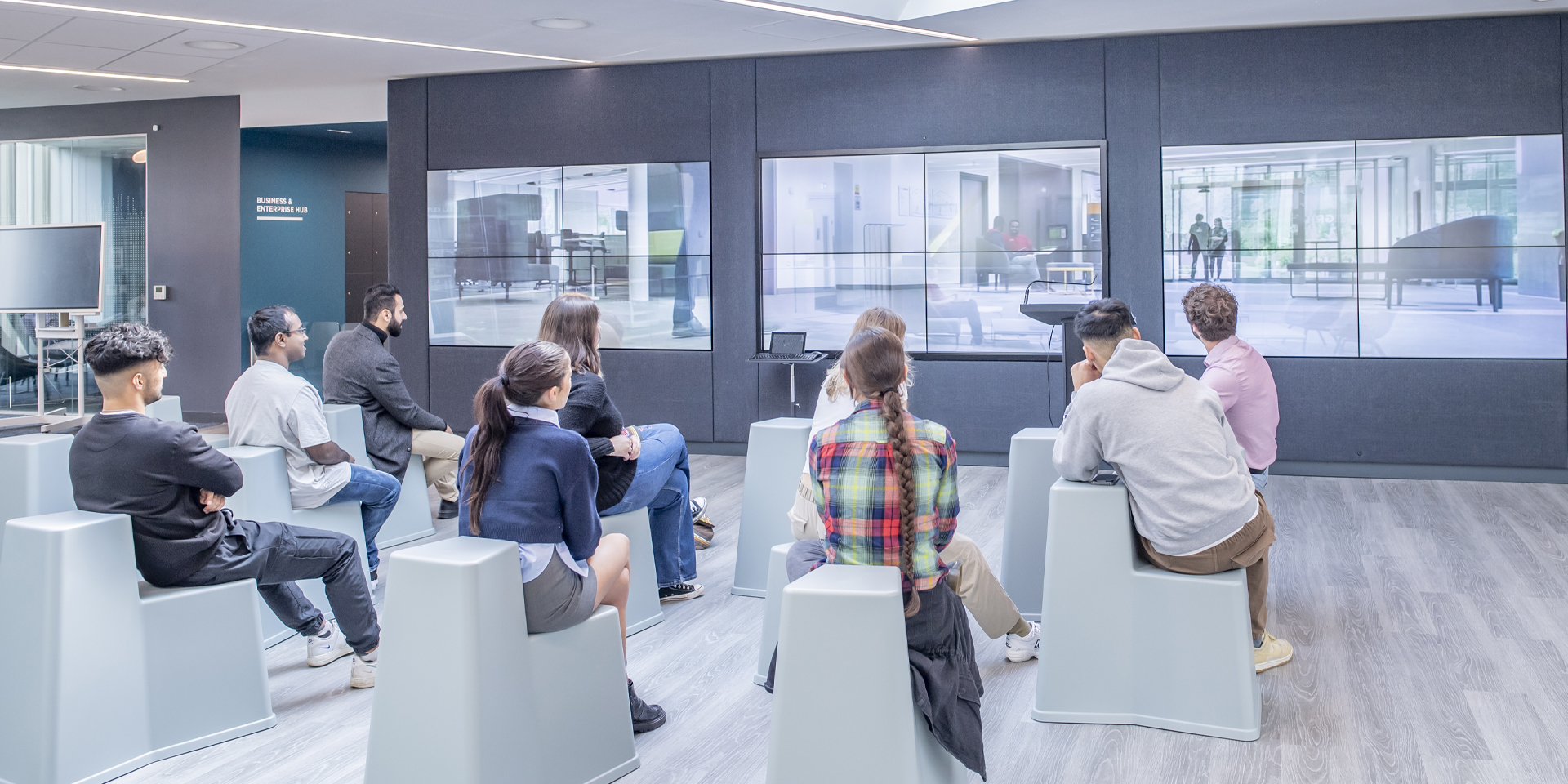 Individuals in attendance at an event watching a screen.