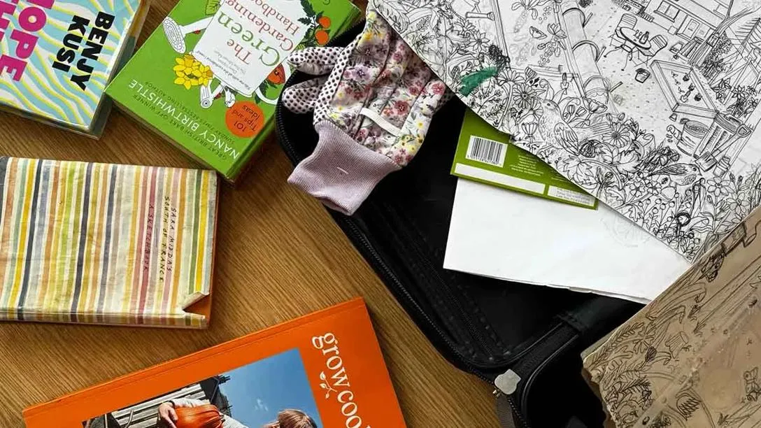 A table strewn with cook books, gardening gloves and a sketch of a vegtetable garden