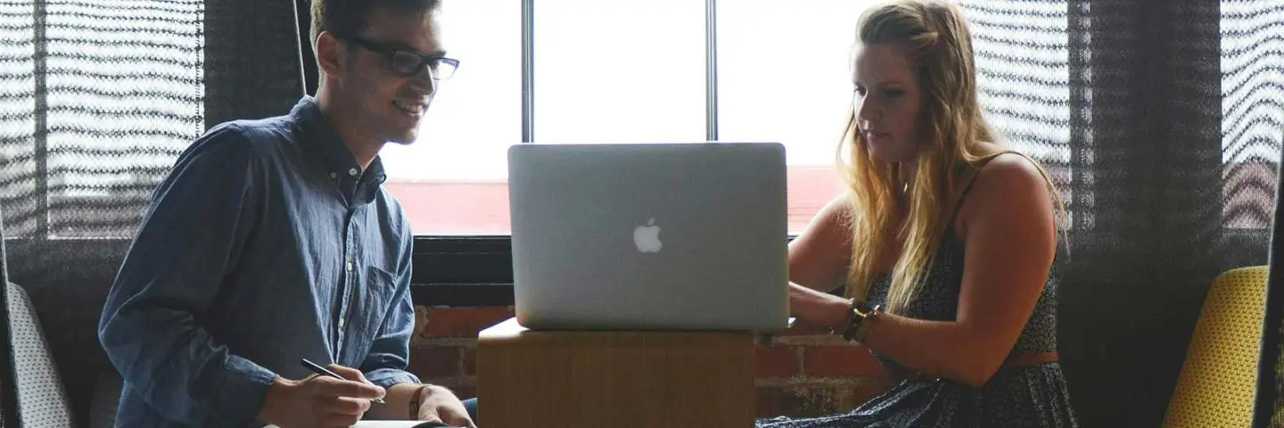 Two individuals work together with a laptop.
