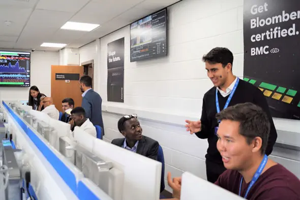 Individuals sitting in a computer lab working together.