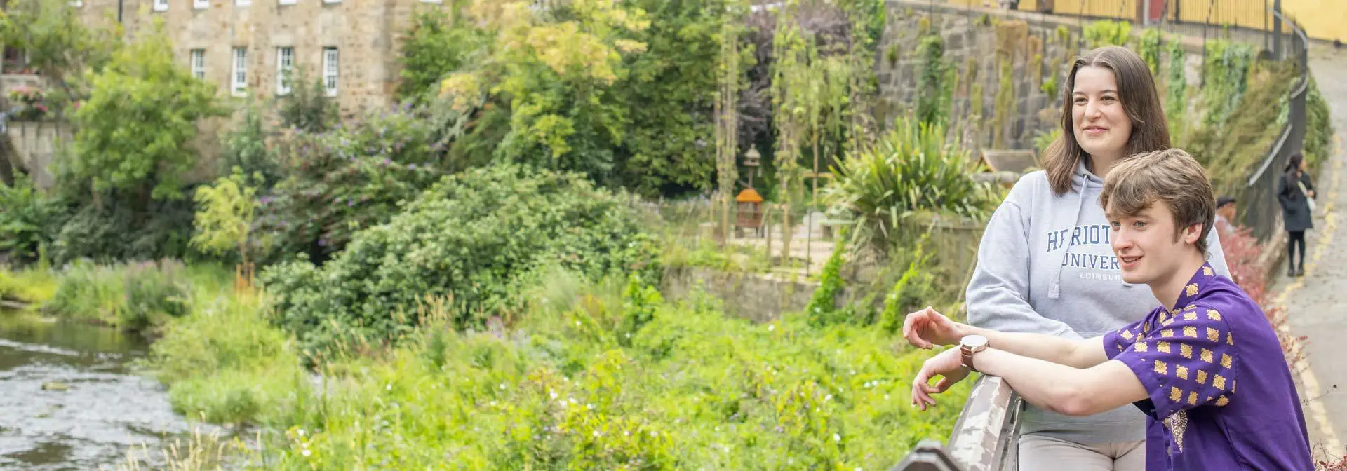 Two students relax and watch the Water of Leith as it flows through the Dean Village.
