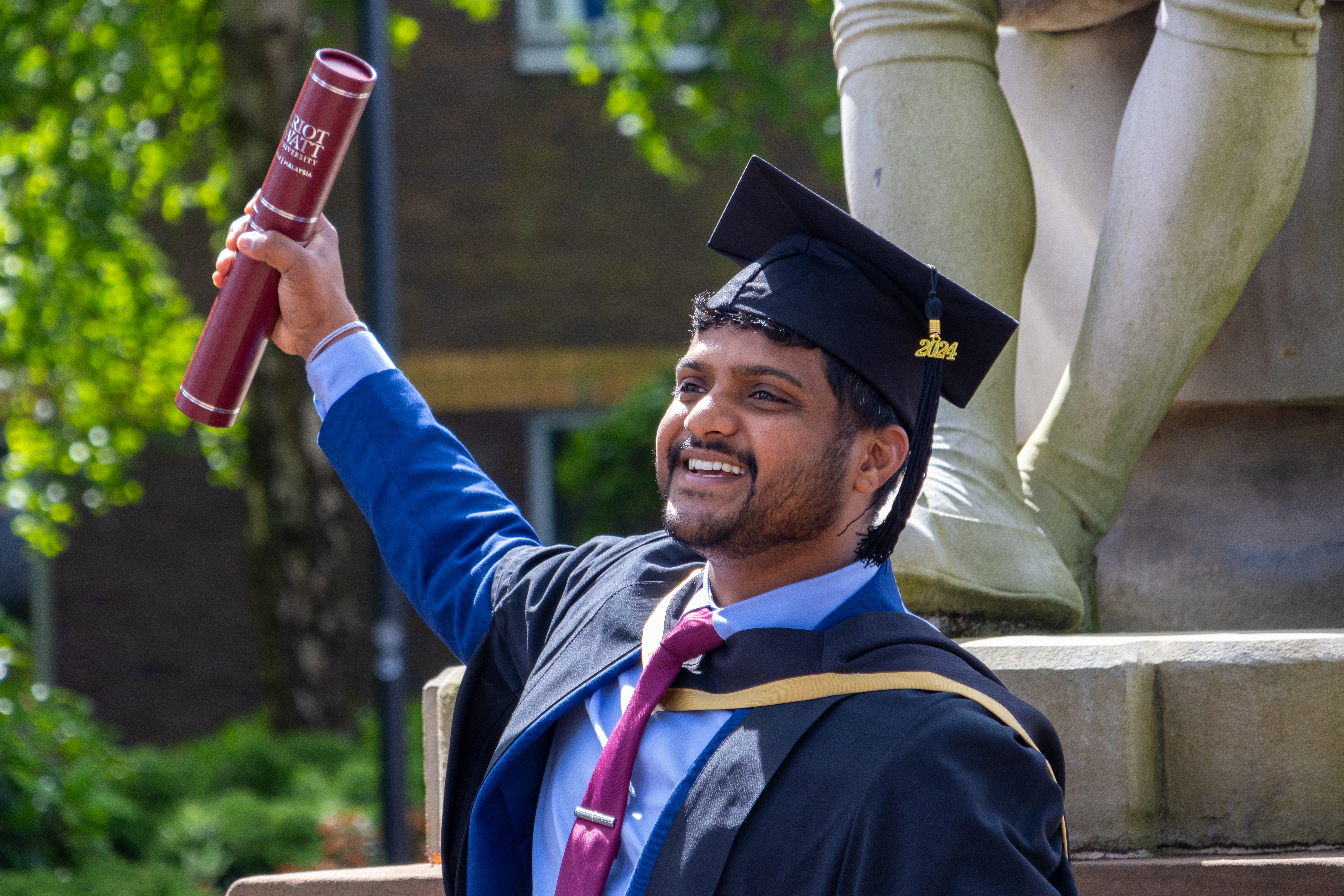 A man holds up a certificate holder on graduation day
