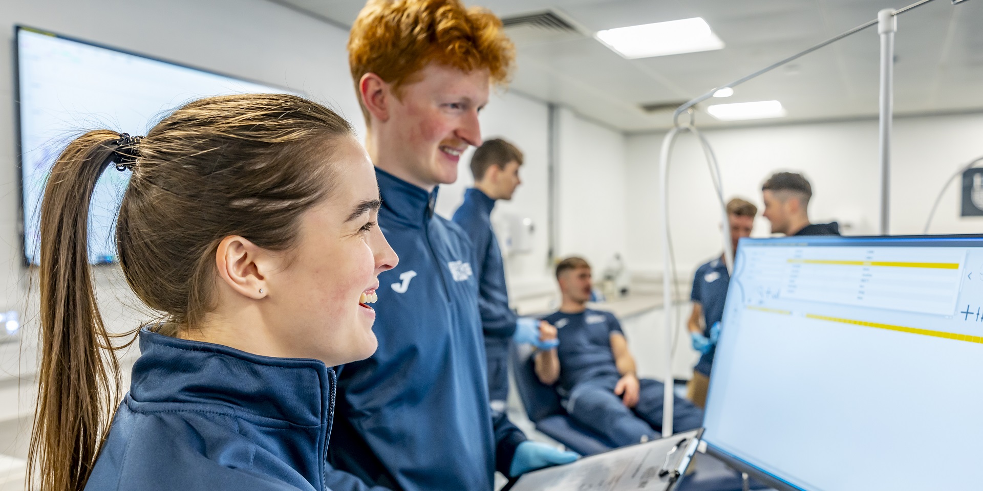 Two students looking at a computer monitor with results of a sporting performance