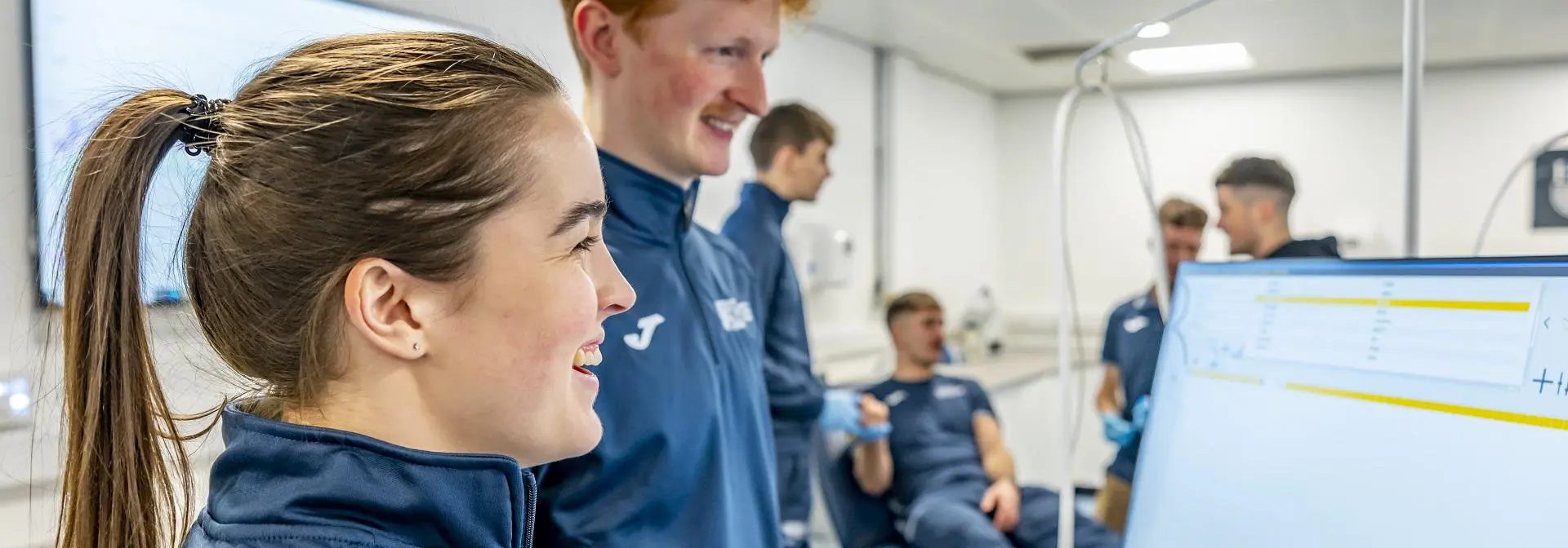 Two students looking at a computer monitor with results of a sporting performance