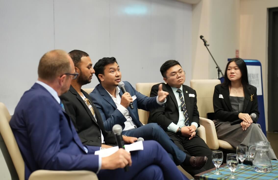 Panel of speakers sitting around table with microphone