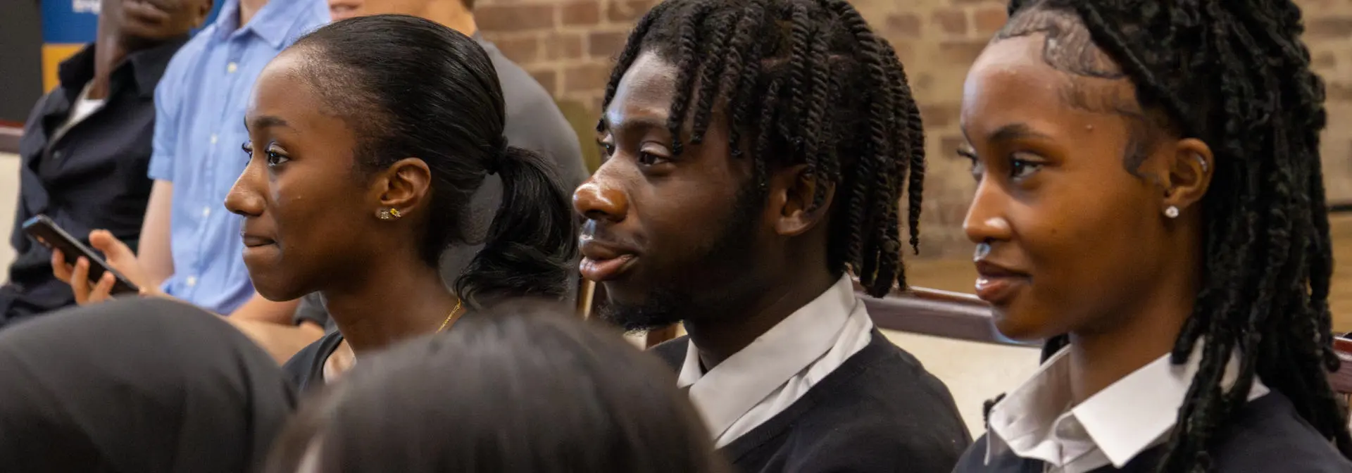 Three individuals dressed in school uniforms sitting in a row.