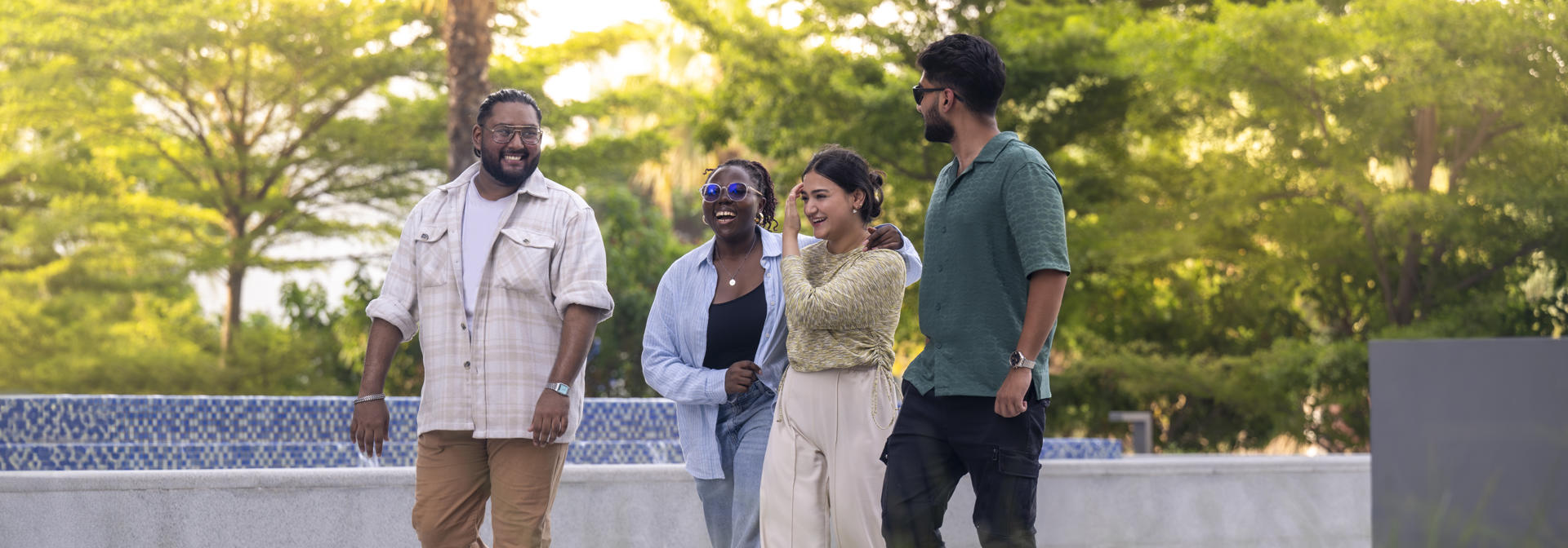 Four smiling young people walking, palm trees in the background