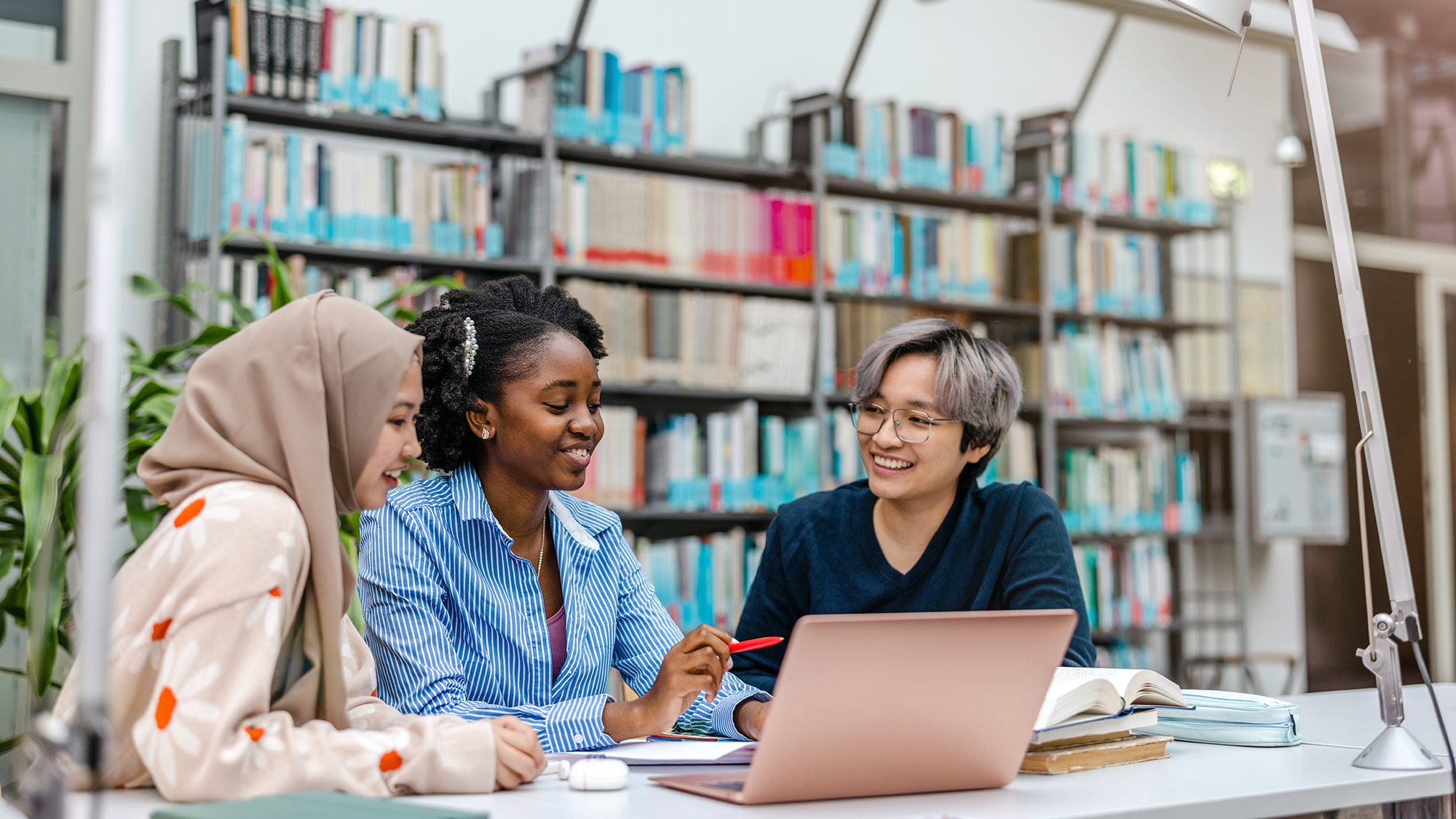 Three students working together in a library