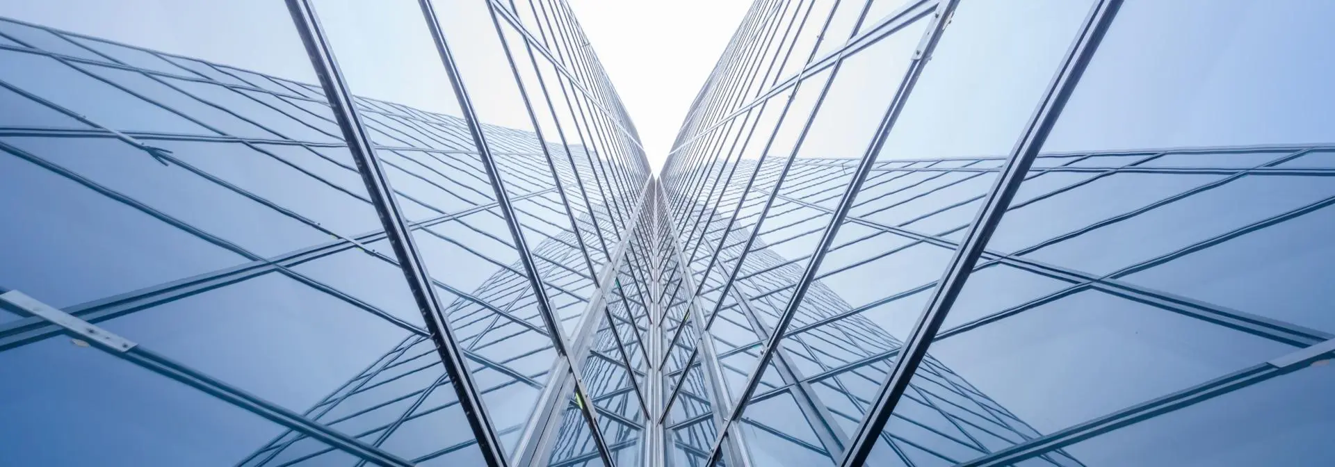 A view looking up at a tall modern and glass building against a clear sky.