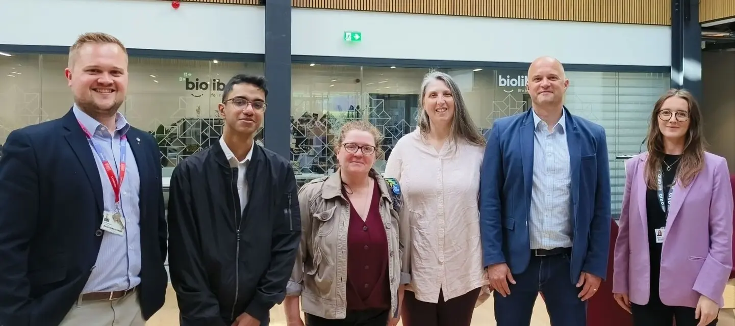 Five people wearing professional outfits standing in a line.