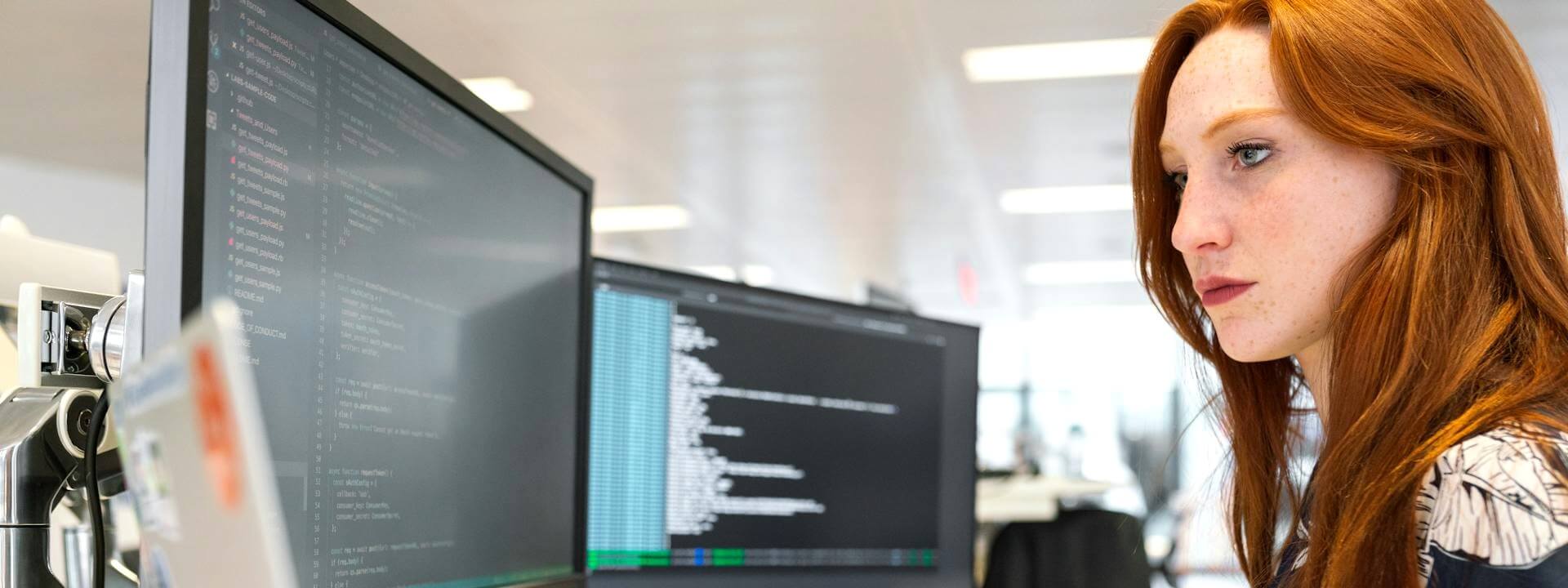 A woman working on a computer looks intently at the screen.