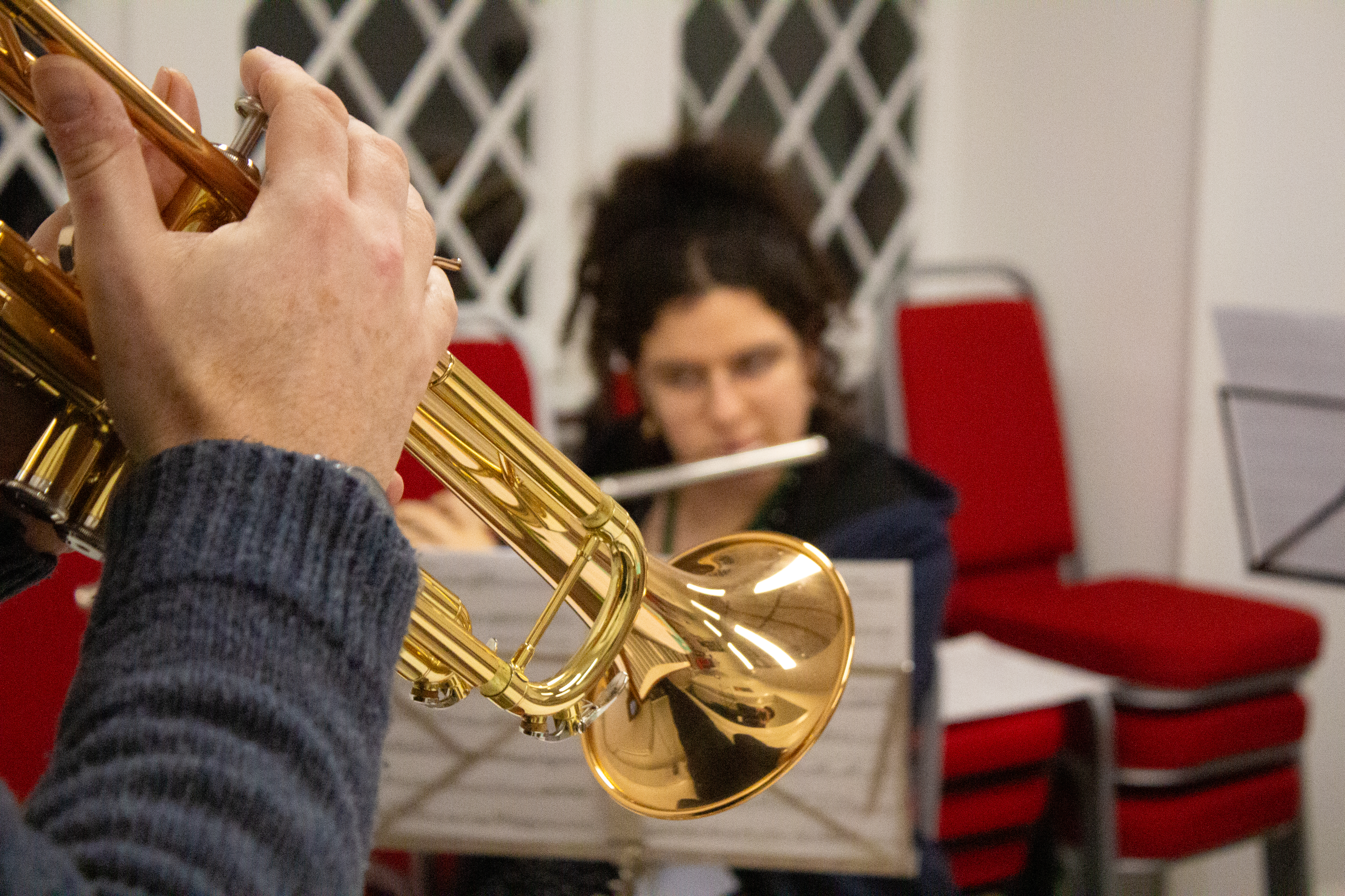 A brass trumpet in a room with red chairs.