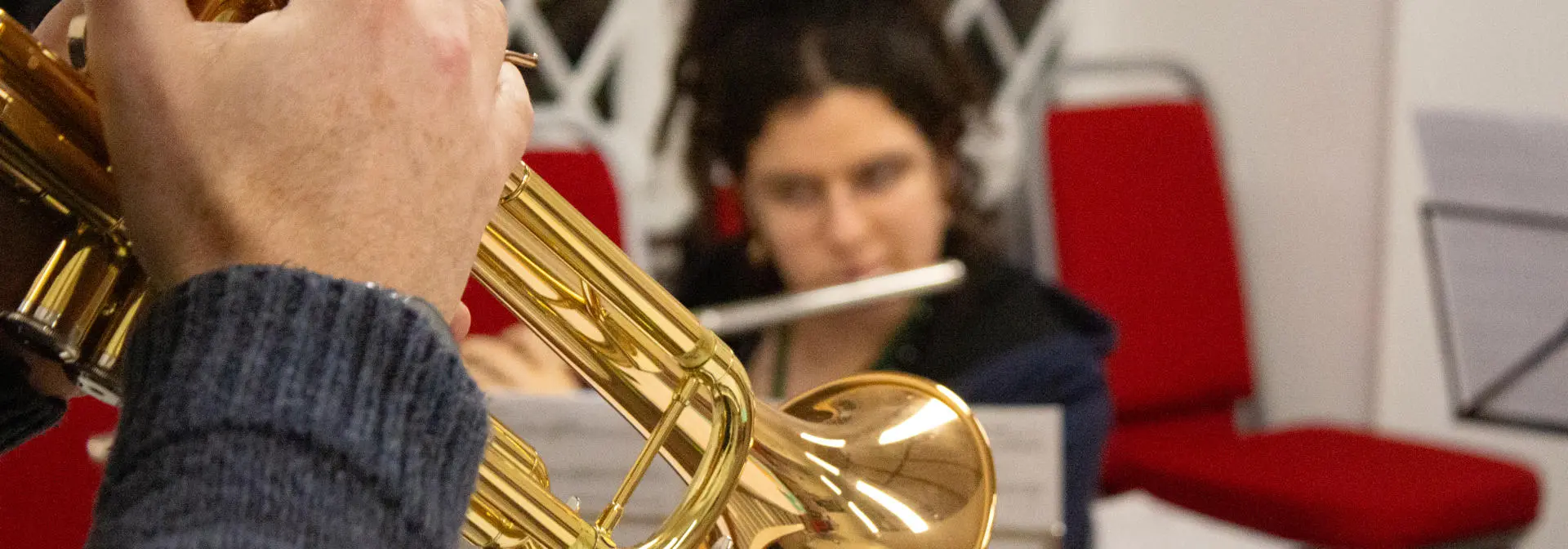 A brass trumpet in a room with red chairs.