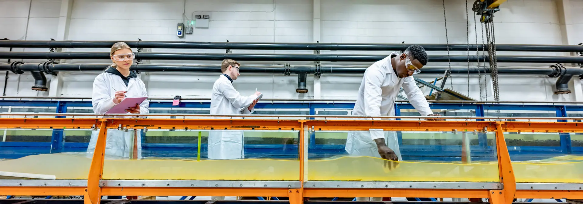Students in lab coats work in a hydraulics laboratory.