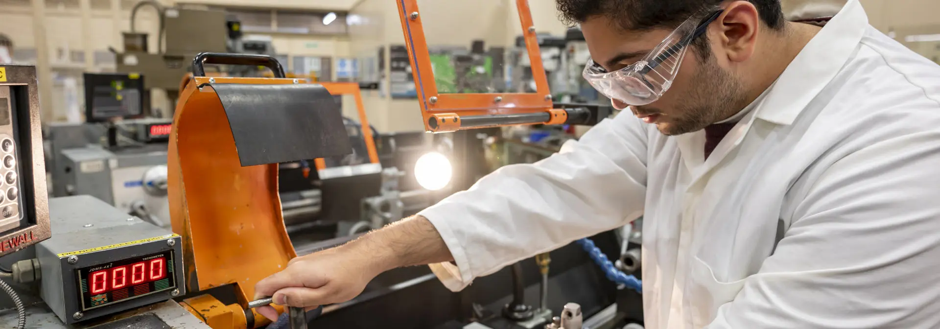 A student tightening a lathe in a large workshop