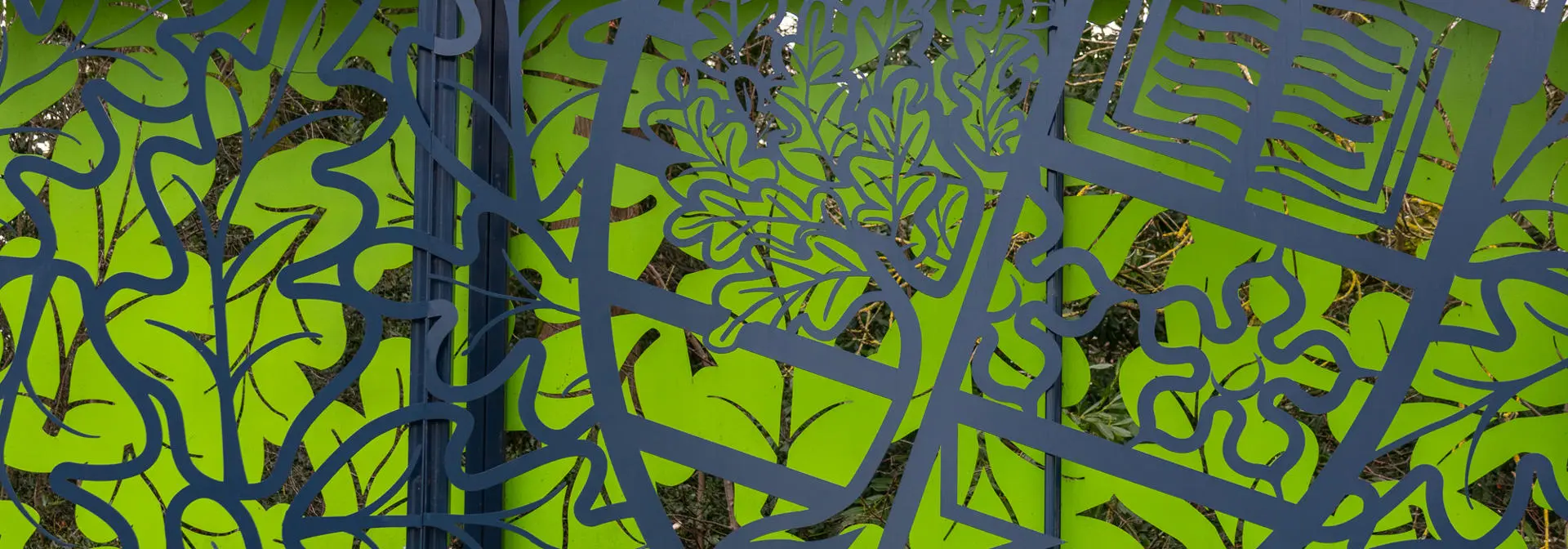 A decorative outdoor metal fence featuring a green background.