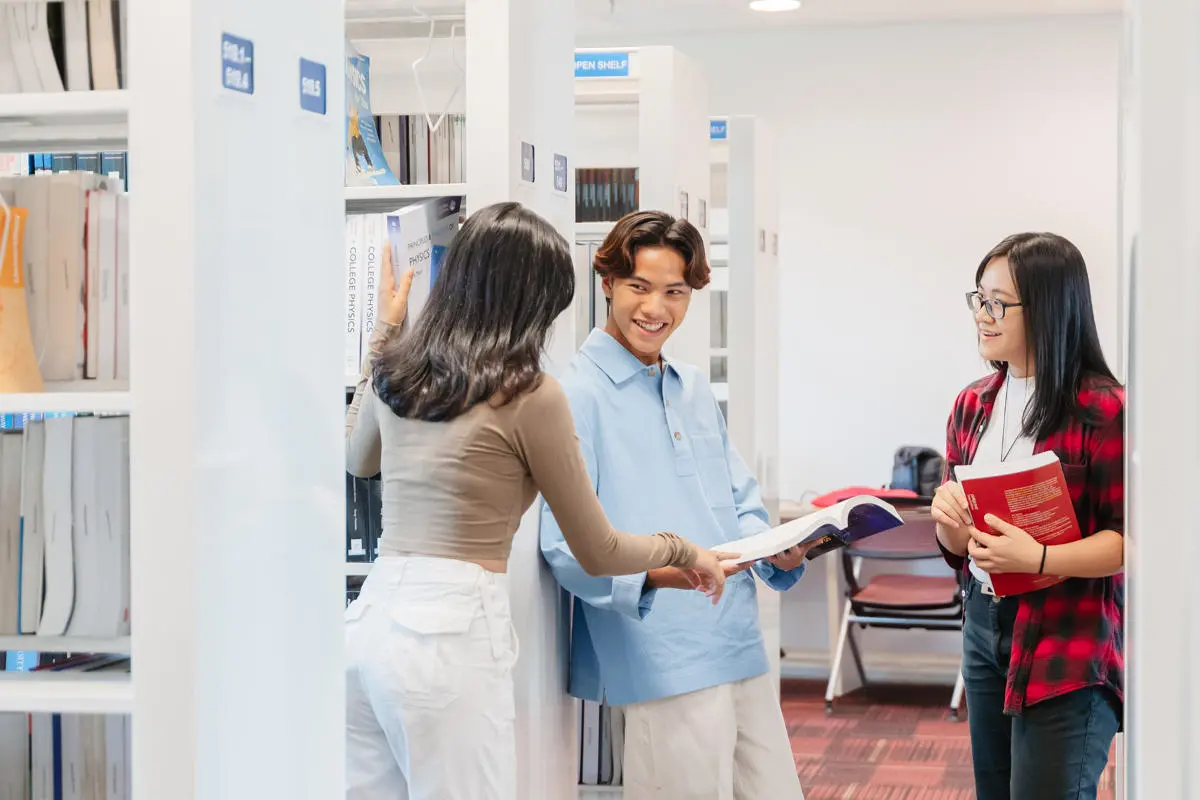 Three students in conversation in the library