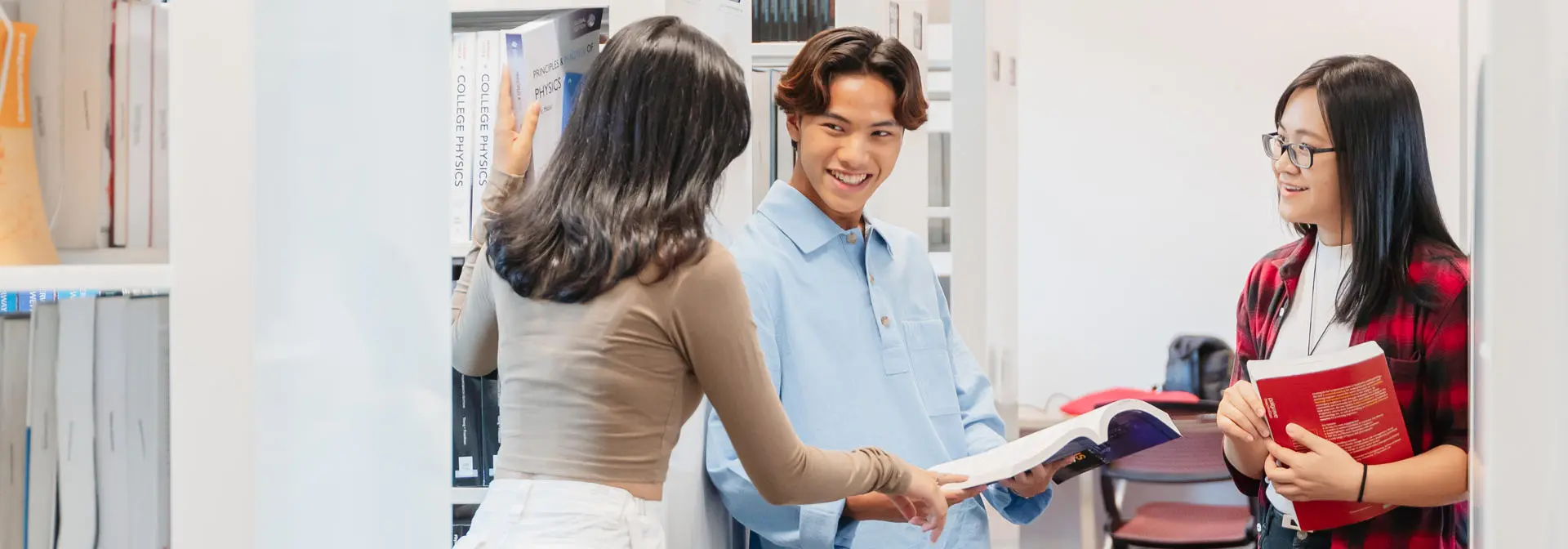 Three students in conversation in the library