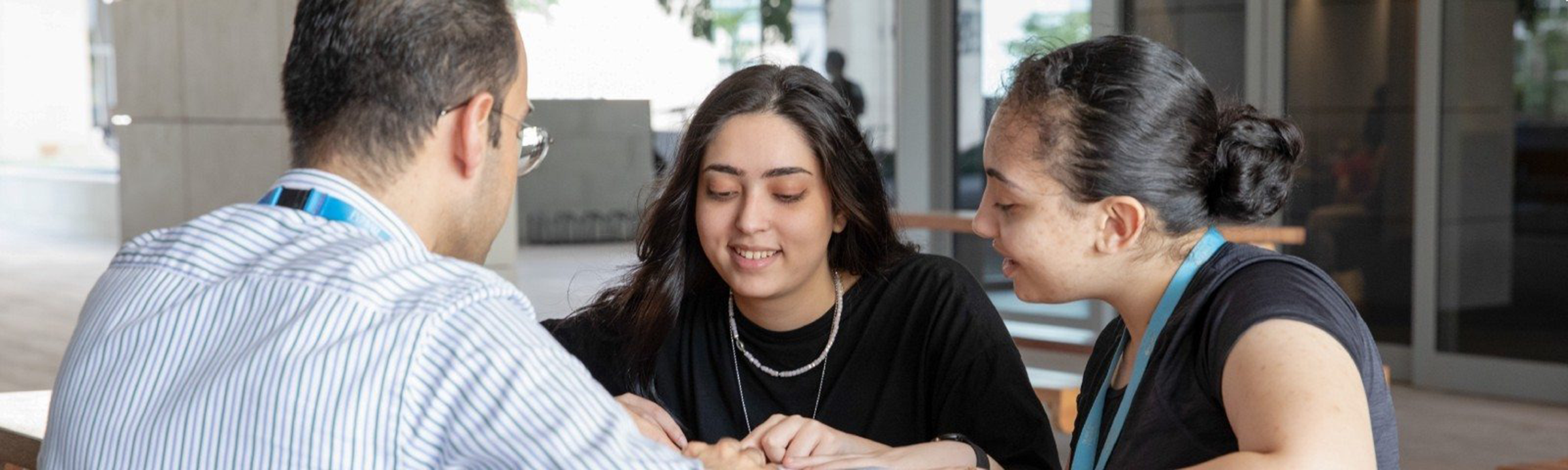 Two individuals sitting and discussing with a member of staff