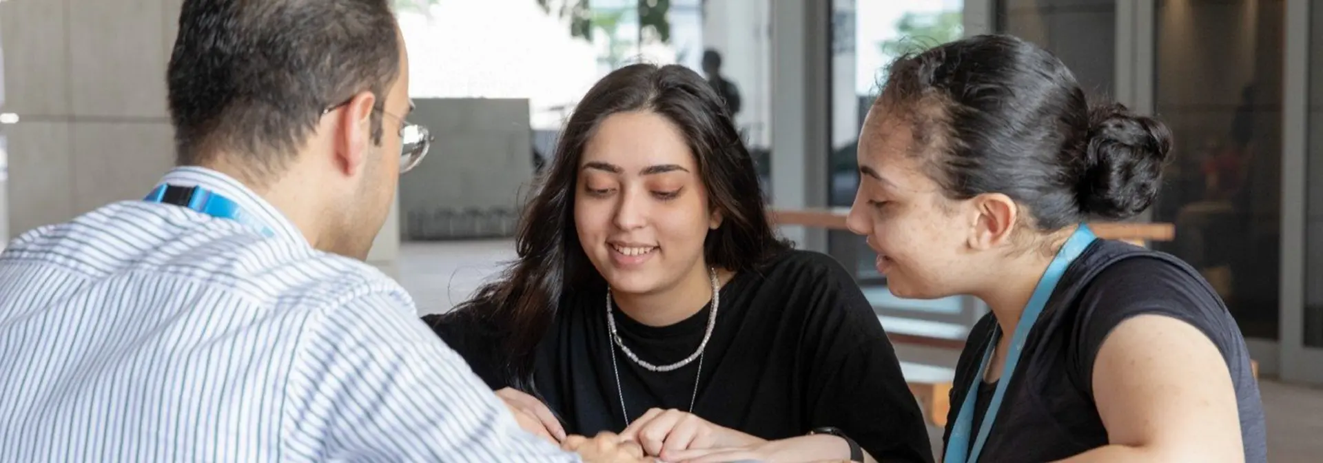 Two individuals sitting and discussing with a member of staff
