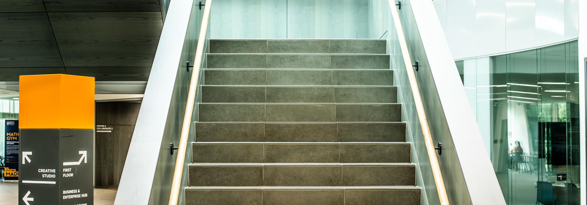 Stairs leading upwards with rails on either side, and a clear signpost to the left of the stairs.