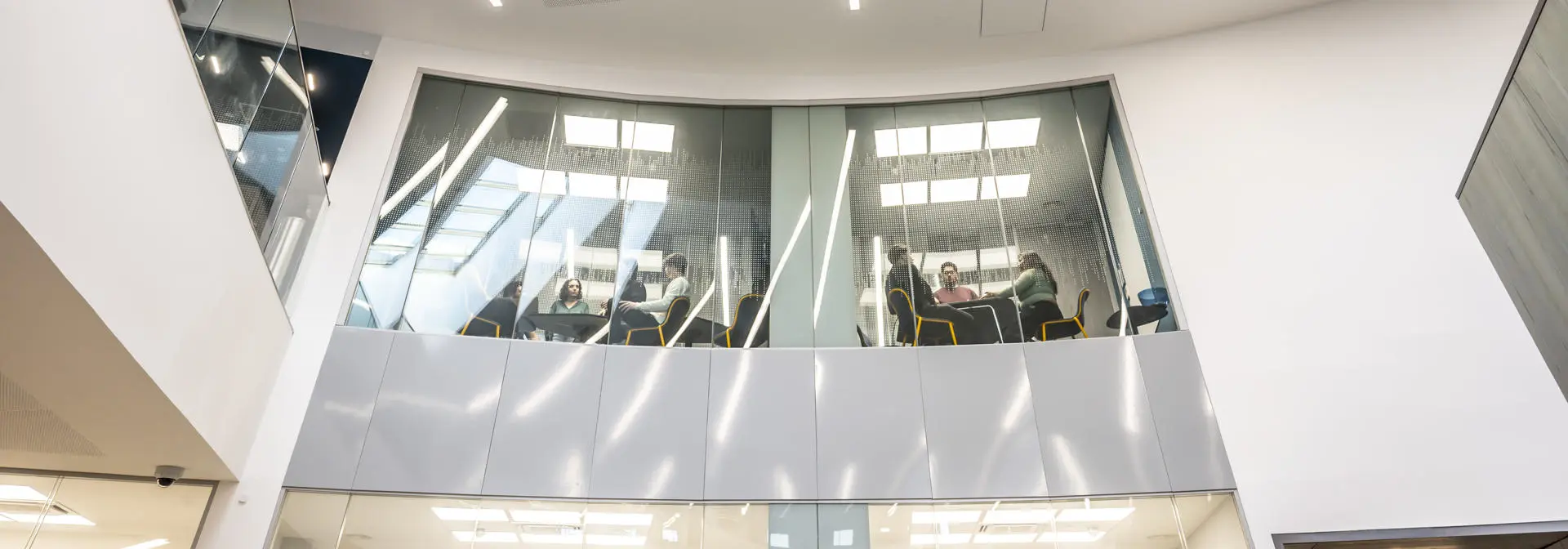 Shot of the inside of the Heriot-Watt GRID building, with a view up from below to glass windowed meeting rooms