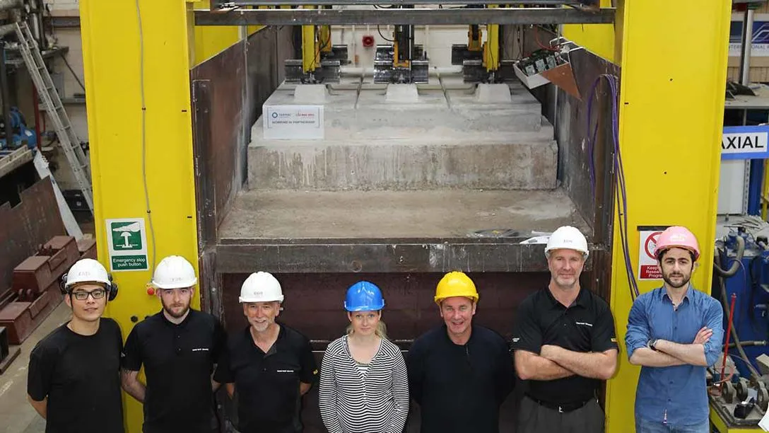 Staff and students wearing protective headgear, standing in front of Geosynthetic Reinforced Soil Retaining Wall testing