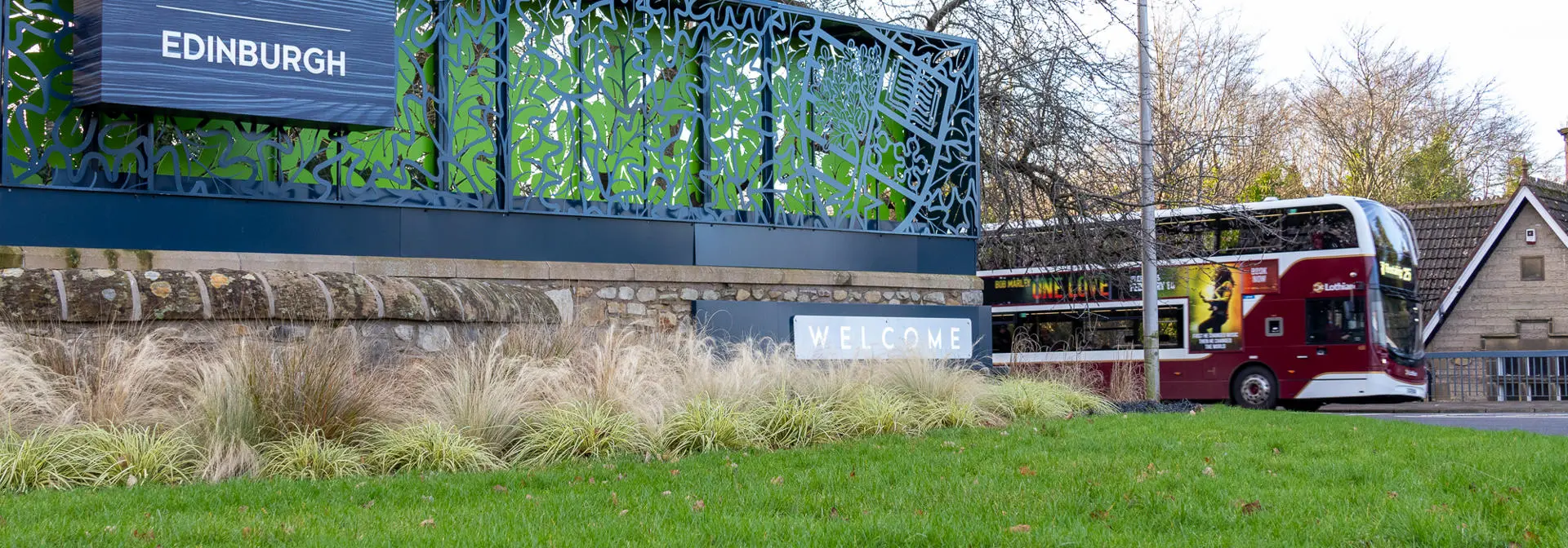 An entrance sign for Heriot-Watt University with a bus driving in the background.