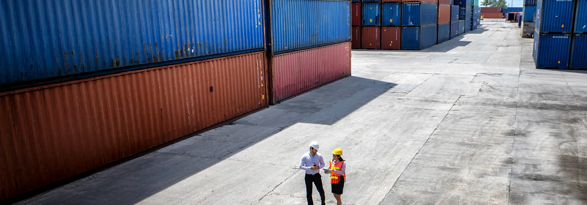 Two logistics managers walking through yard of loading containers.