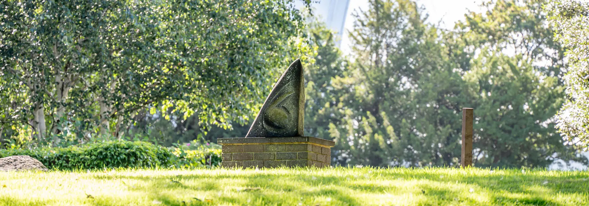 Triangular statue on a patch of grass.