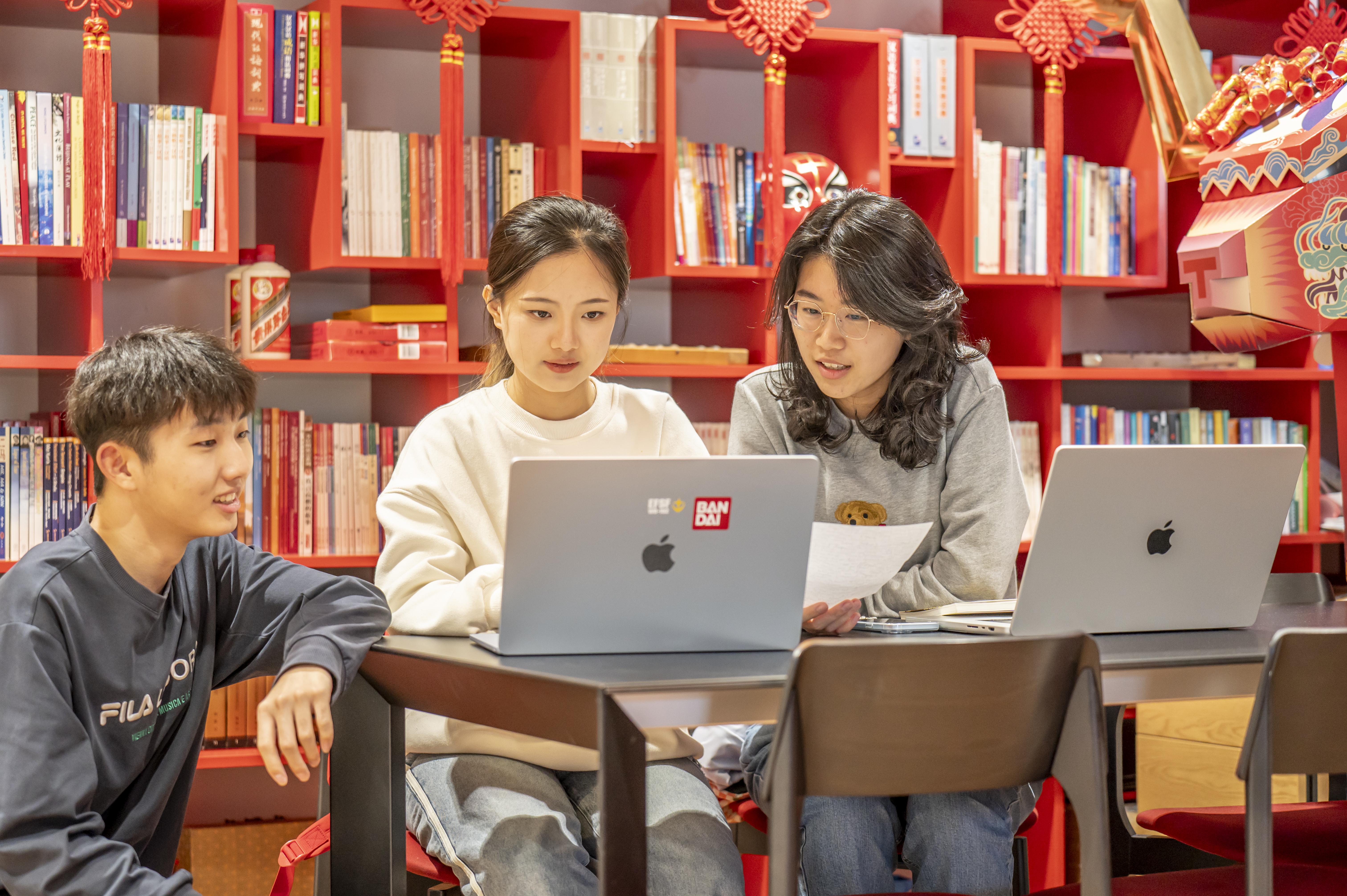 International students sit at a table with shelves of Chinese books and decorations behind them