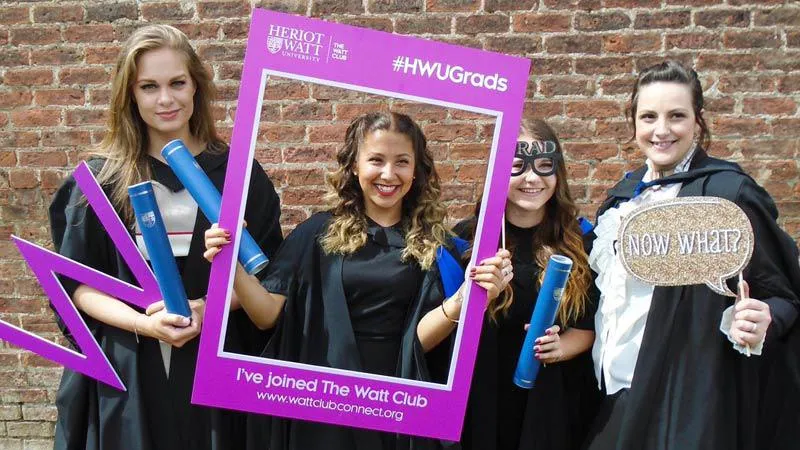 Graduates holding sign reading "I've joined the Watt Club"