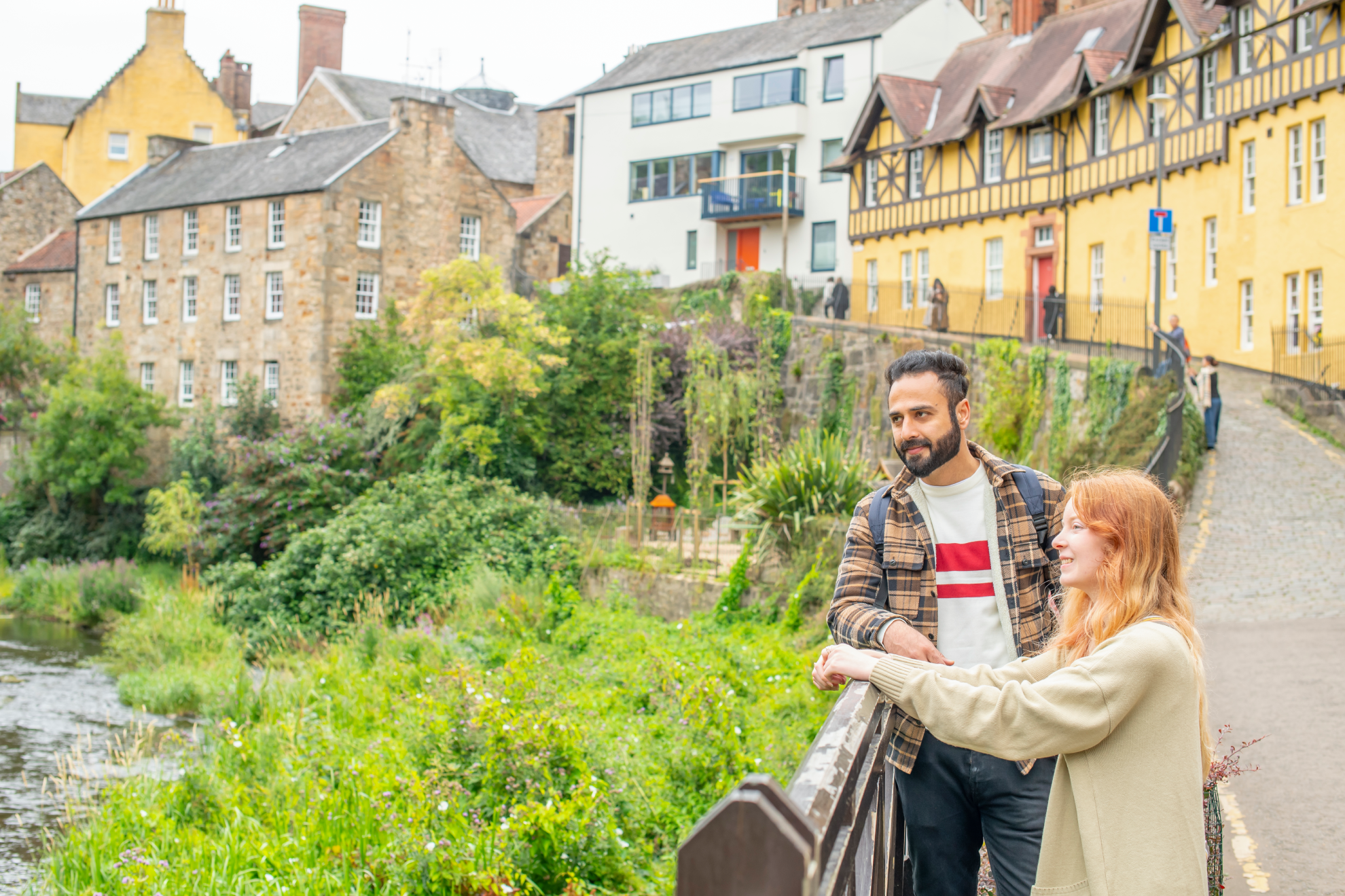 Two students standing by a fence in Dean Village, Edinburgh overlooking the Water of Leith.