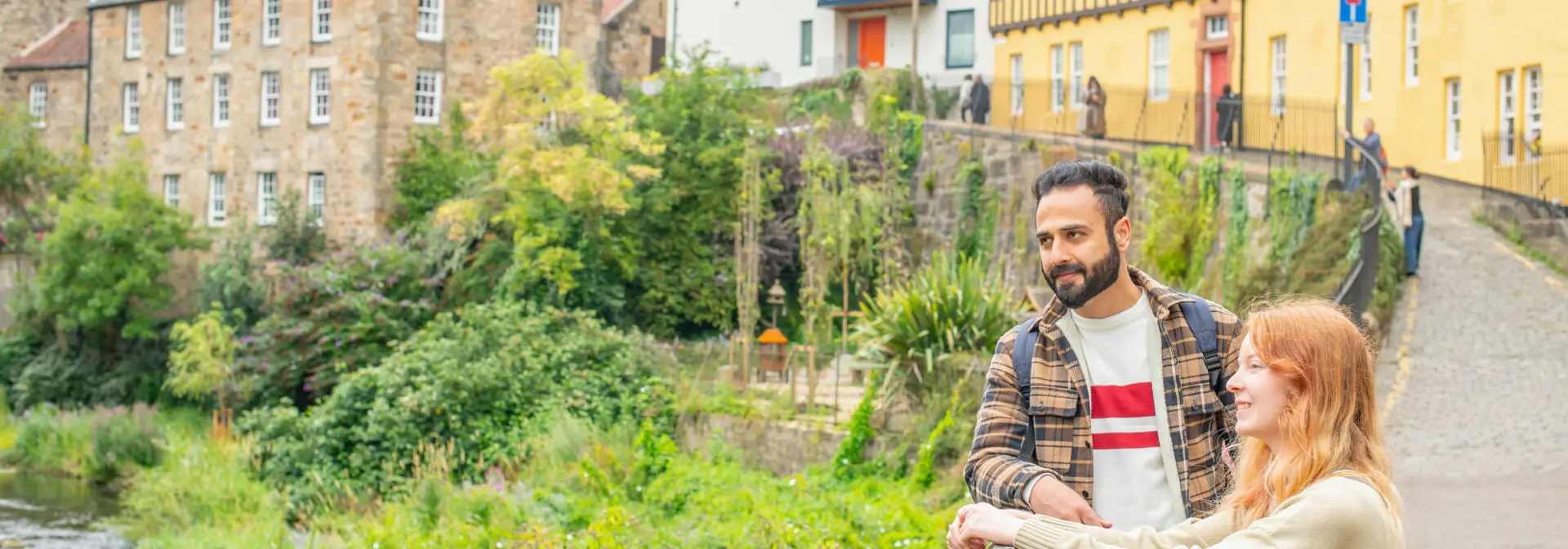Two students standing by a fence in Dean Village, Edinburgh overlooking the Water of Leith.