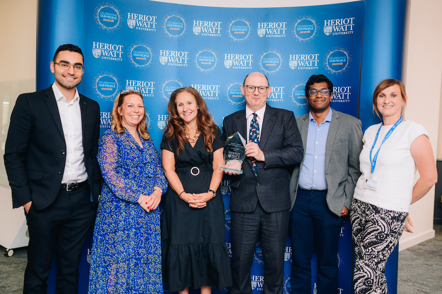 Six individuals smiling as they receive an award. 