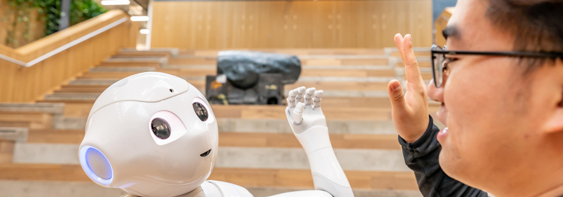 Robot high-fiving a man in the National Robotarium