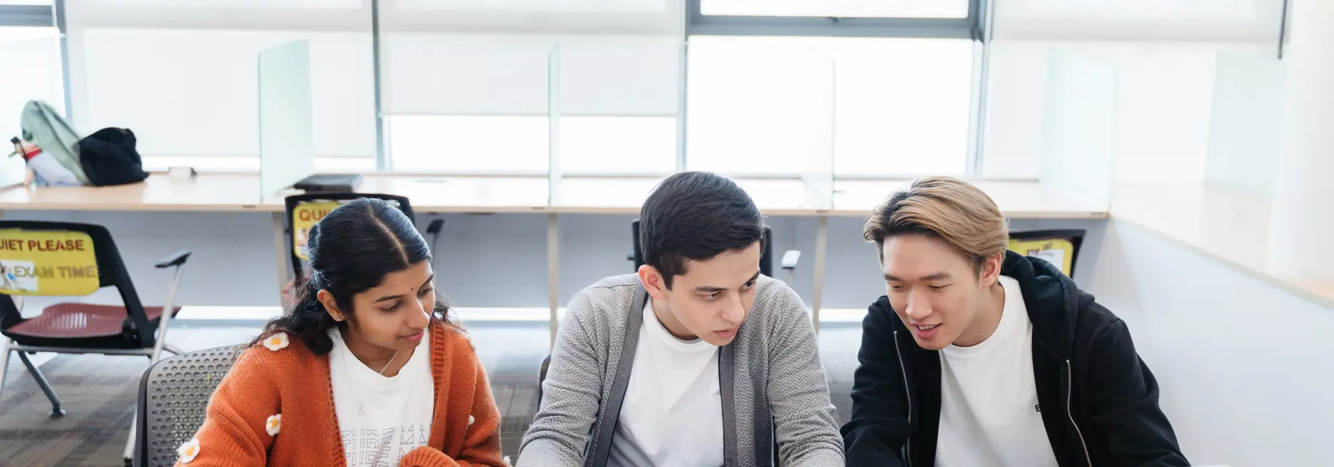 Two individuals sitting at a desk speaking to a staff member at Heriot-Watt