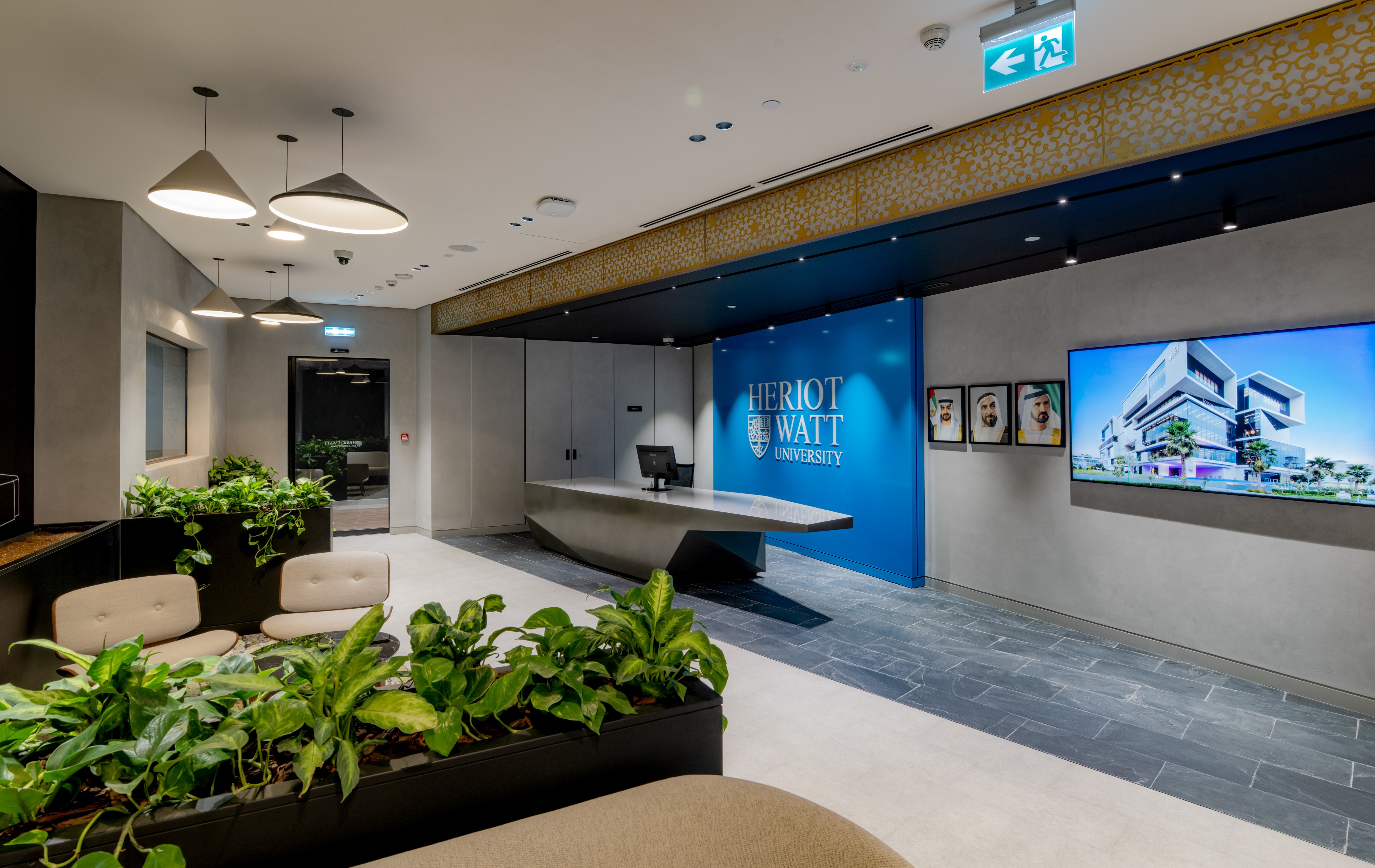 reception with a grey stone desk infront of wide blue panel with Heriot-watt logo 