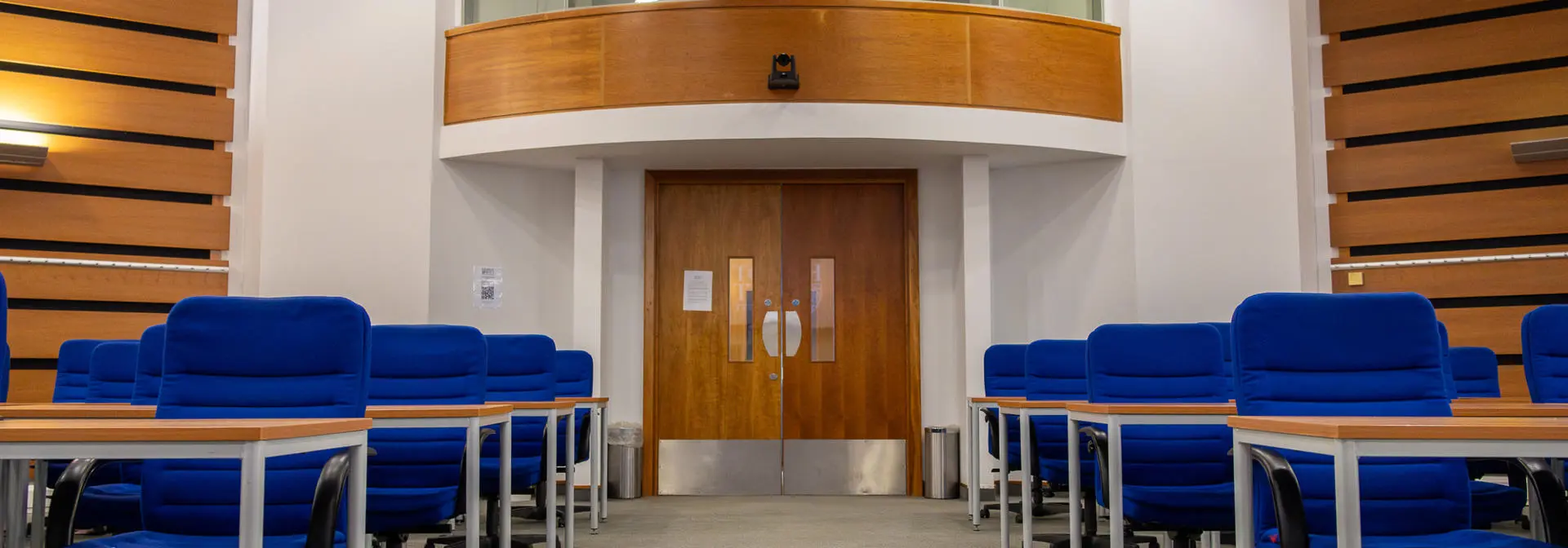 An empty room full of blue chair and desks set up for an assessment.