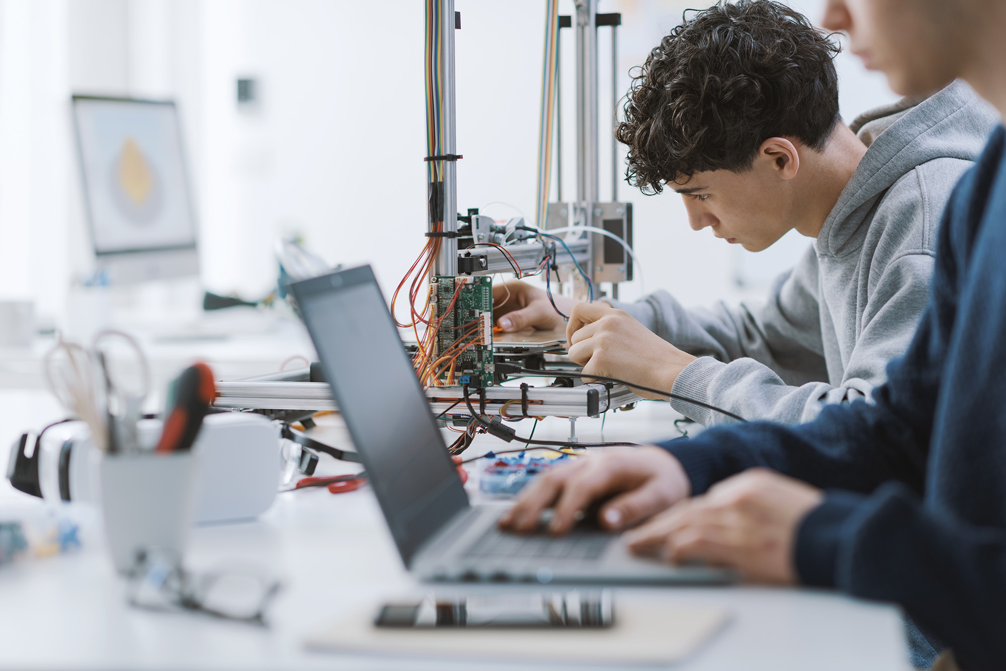 Two individuals working with cables and computer science programmes