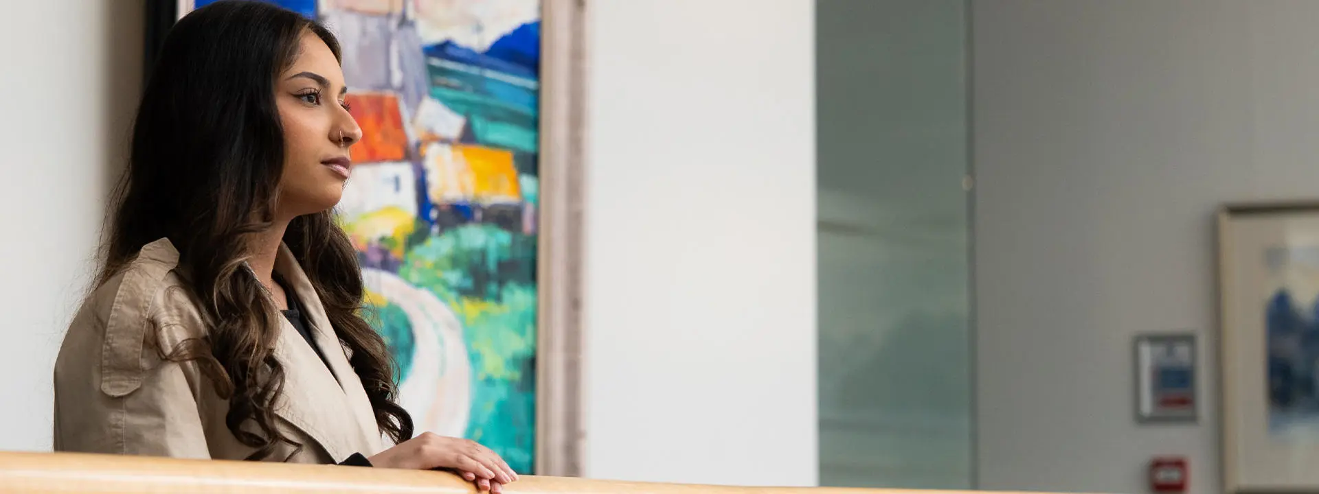 Scholarship recipient Shanzay standing in front of a colorful painting.