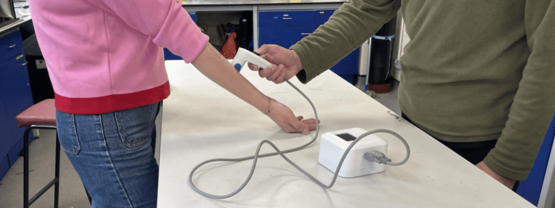 Two people using the vibroacoustic sensor- which measures material changes in each layer of skin.