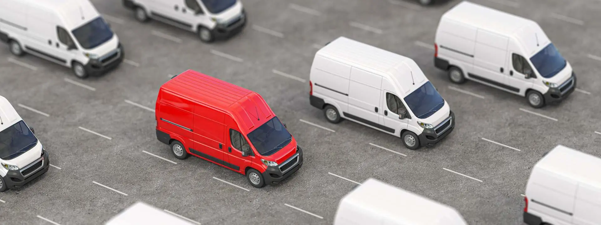 One red van parked beside multiple white vans.