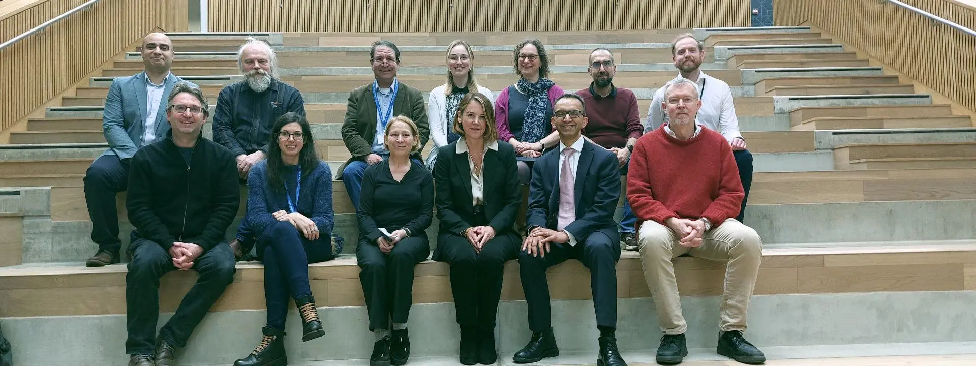 A group of people in business attire are sat across a large stairway at The National Robotarium